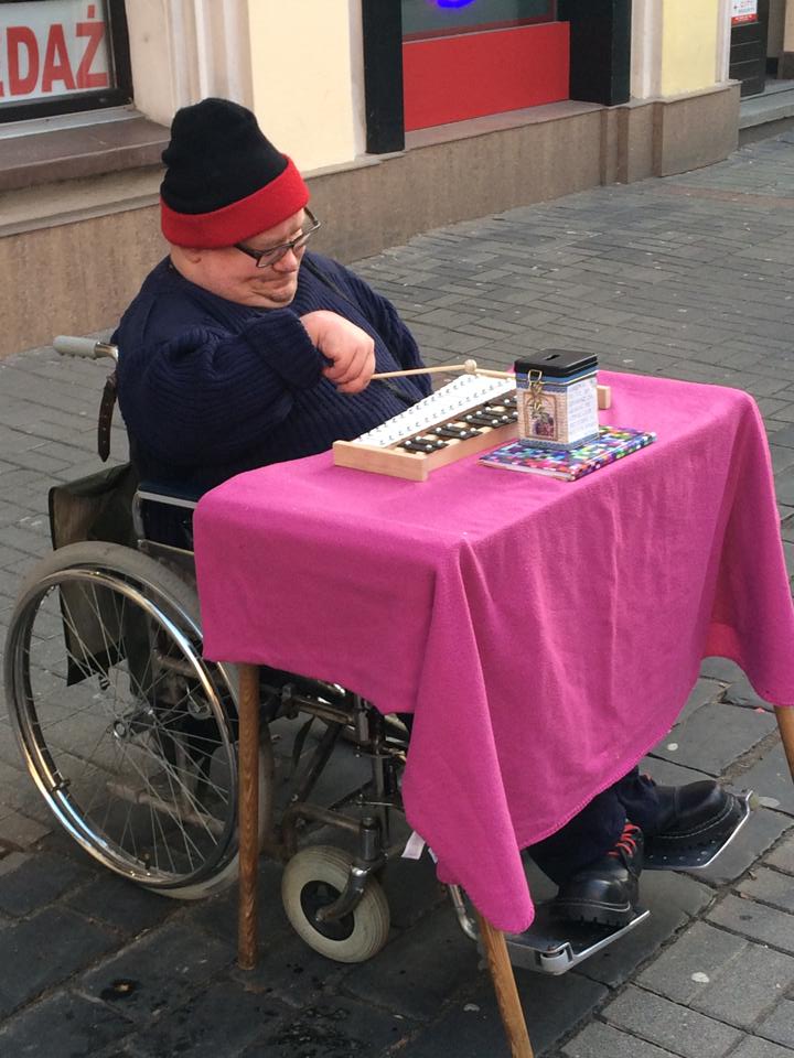 Na grafice człowiek na wózku grający na cymbałkach.