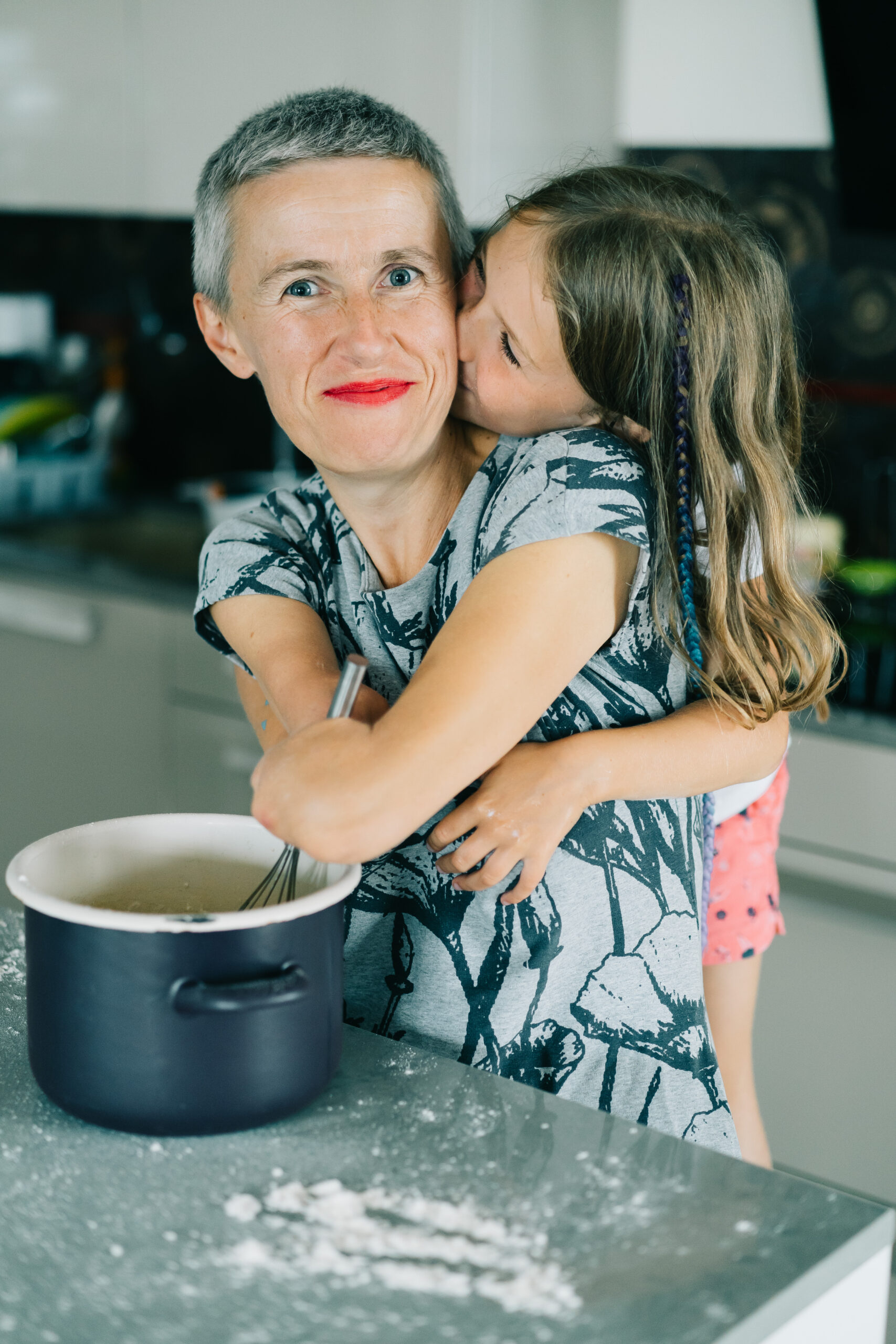 Katarzyna Rogowiec gotuje w kuchni. Od tyłu przytula ją jej córka.