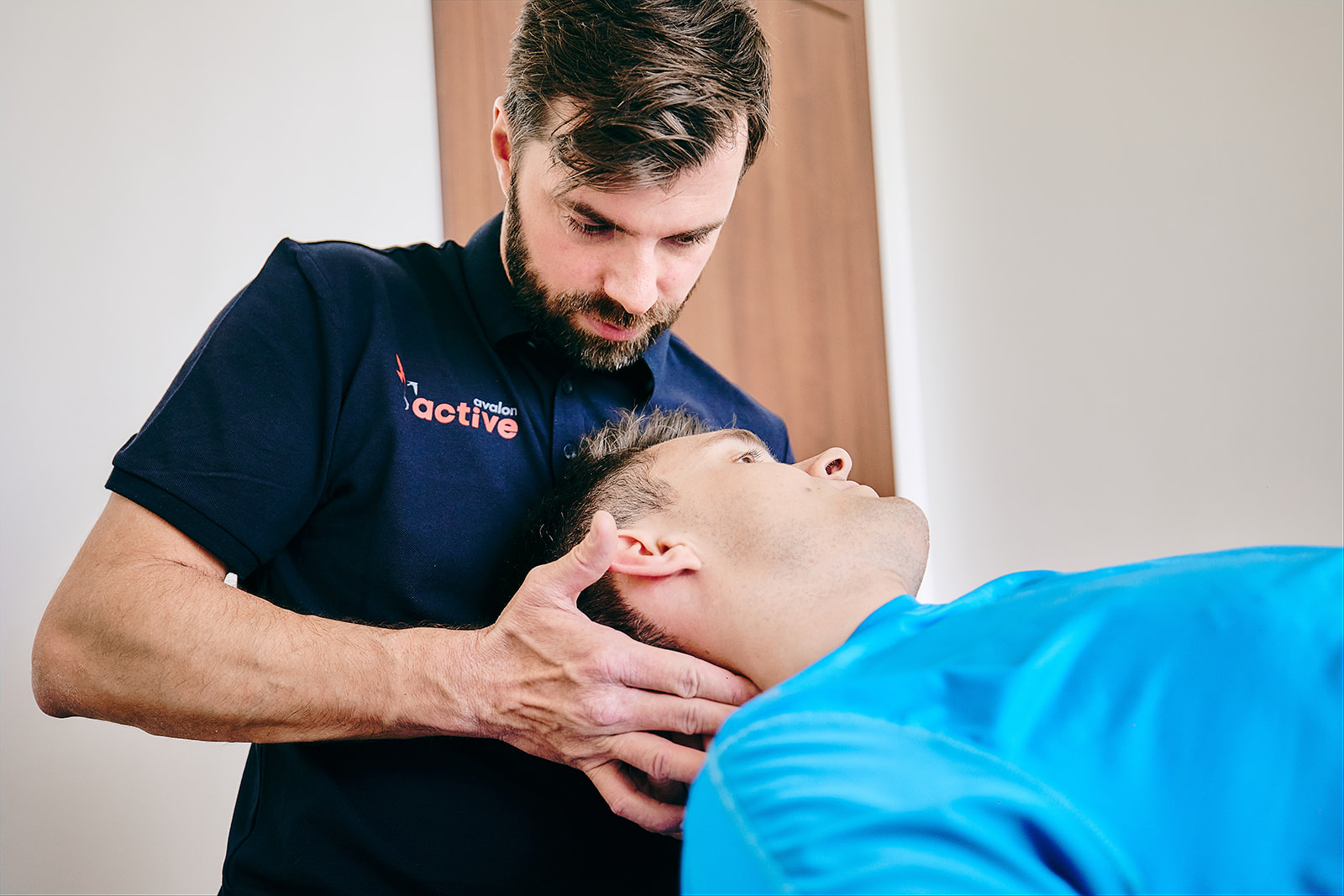 Na zdjęciu fizjoterapeuta rotuje głowę pacjenta.